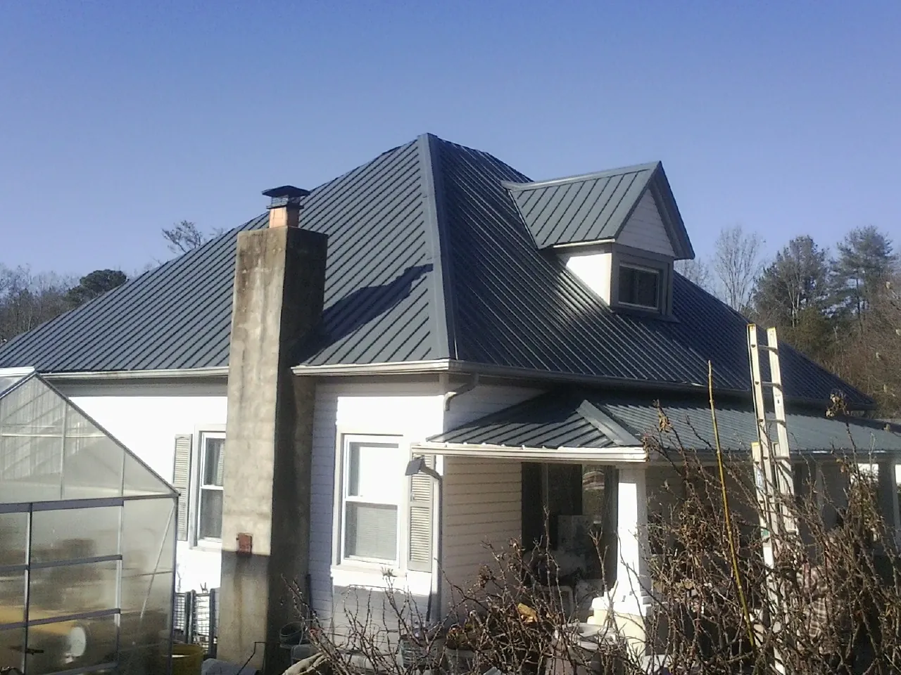 Dark blue standing seam metal roof on a white farmhouse with dormer — Slate & Tile Roof Repair by Roofing Brothers in North Bergen