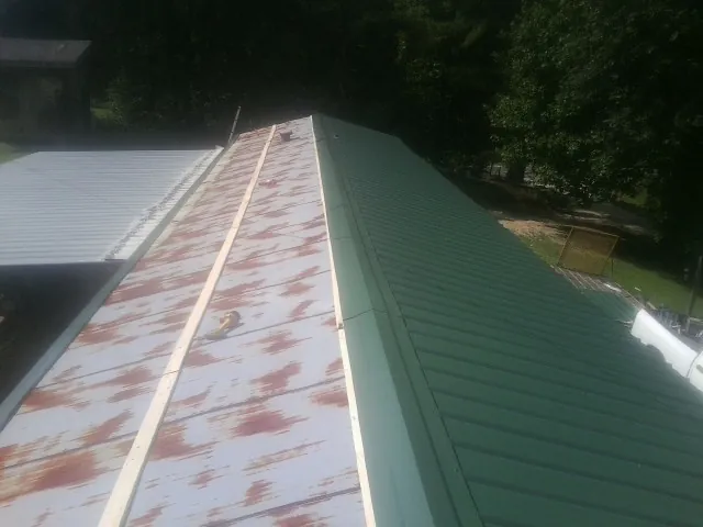 Old rusted panels beside newly installed green metal roofing — Wind Damage Roof Repair by Roofing Brothers in North Bergen