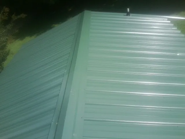 New green metal panels meeting at the ridge of a roof — Flat Roof Repair work by our crew in North Bergen