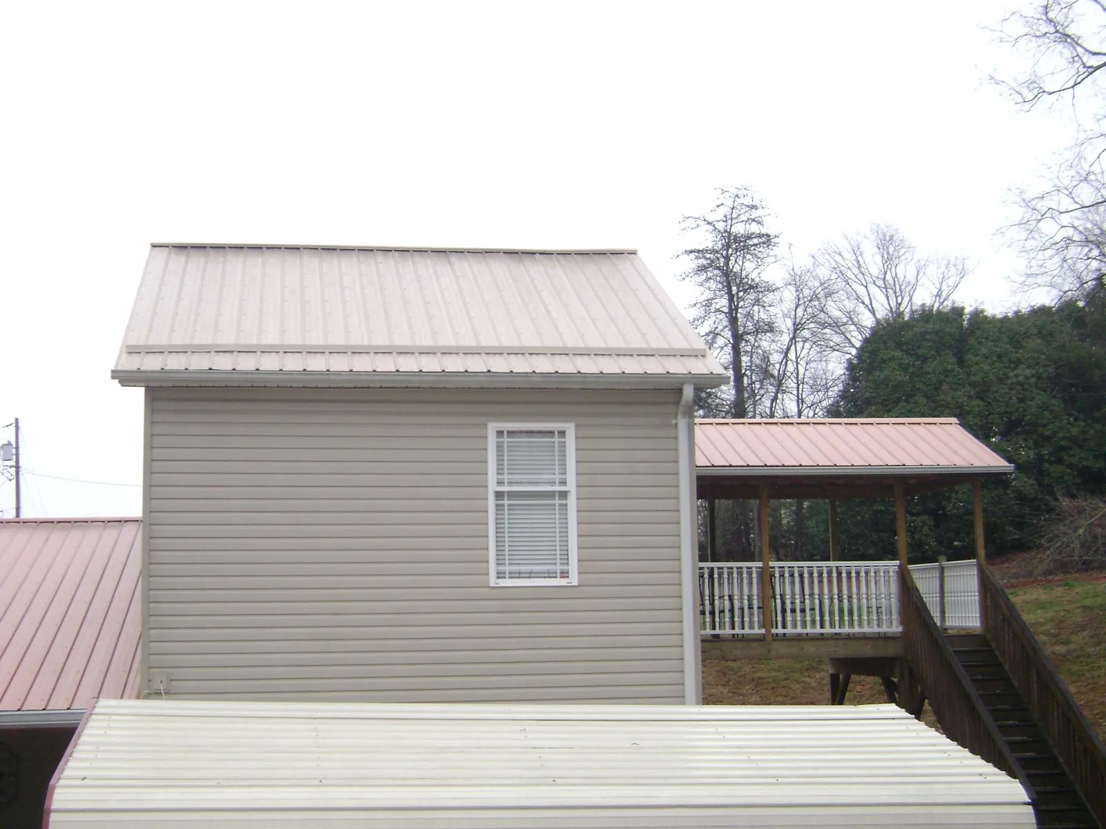 Tan metal roofs on a two story addition and attached porch, from a Roof Replacement job in North Bergen