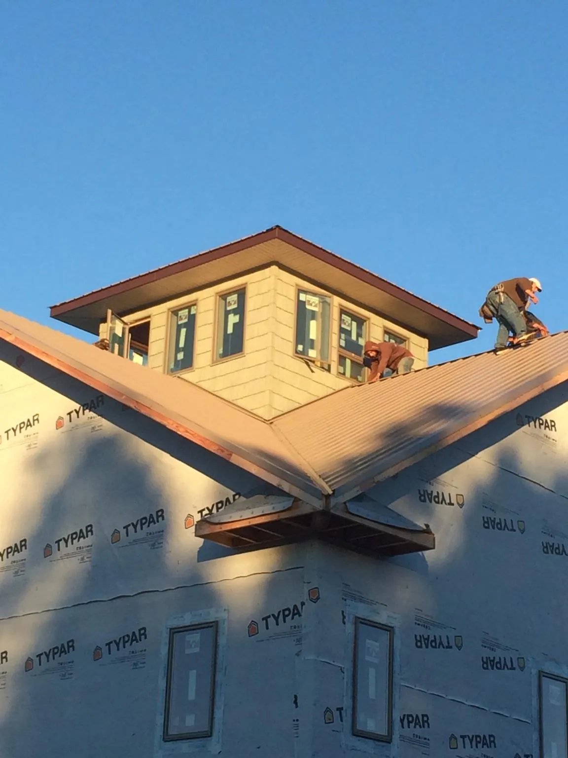 Roofers working around a rooftop cupola on a new metal roof at sunset — Roof Waterproofing in North Bergen by Roofing Brothers